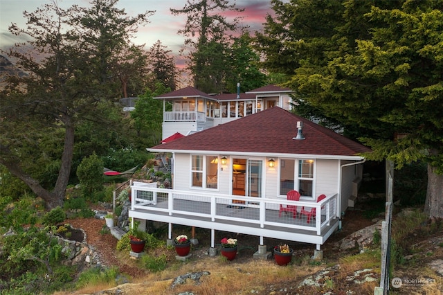 view of front facade featuring a shingled roof and a balcony