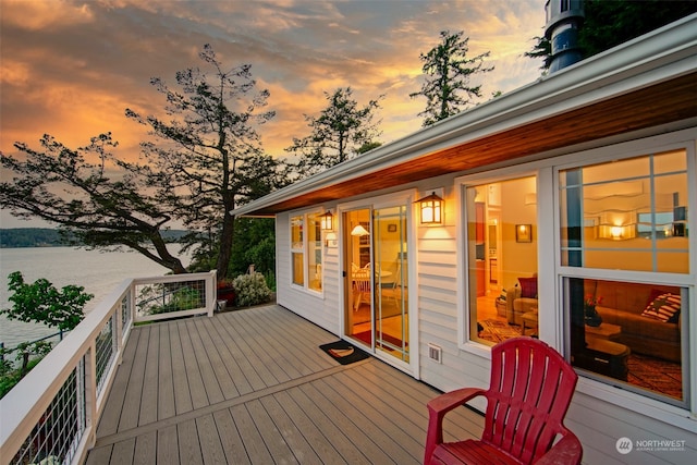 deck at dusk featuring a water view