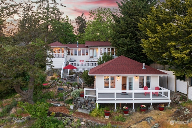 view of front of property with stairway, roof with shingles, a deck, and fence