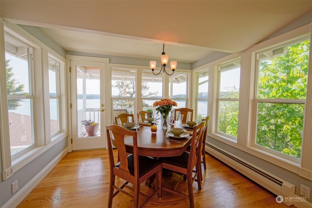 sunroom featuring a water view, a baseboard heating unit, wood finished floors, and a healthy amount of sunlight