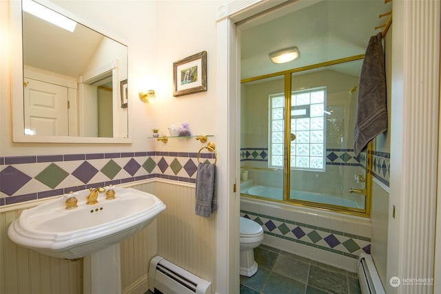 full bath featuring combined bath / shower with glass door, wainscoting, a baseboard heating unit, and toilet