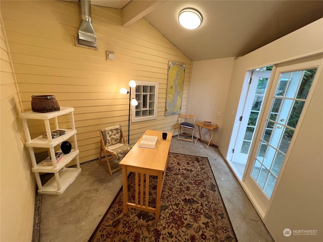 office area with wooden walls, lofted ceiling with beams, and unfinished concrete floors