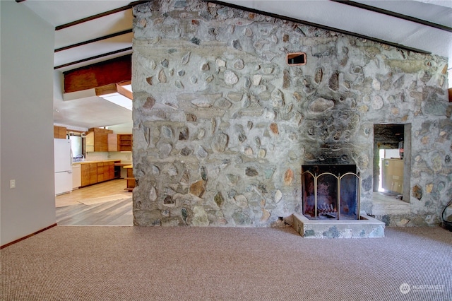 unfurnished living room featuring light carpet, a stone fireplace, and lofted ceiling with beams