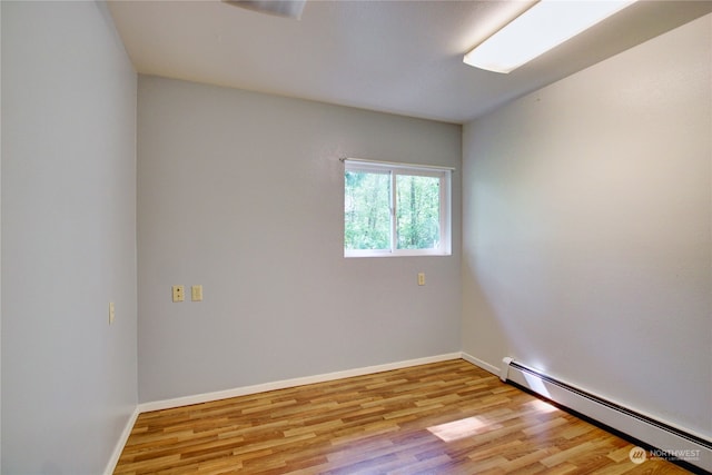 empty room with light hardwood / wood-style floors and a baseboard heating unit