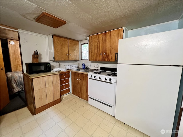 kitchen with white appliances, a textured ceiling, and light tile floors