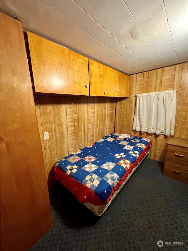 carpeted bedroom featuring wooden walls