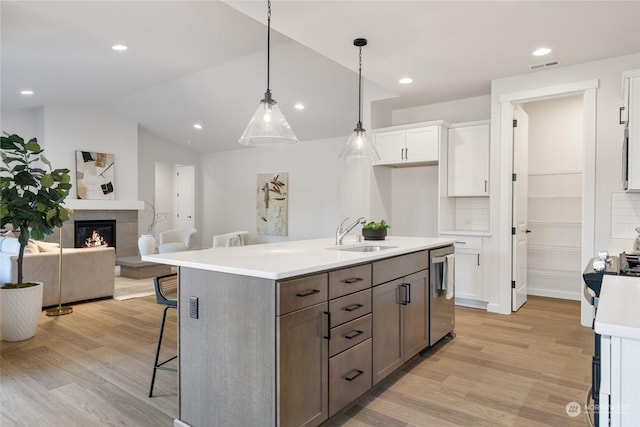 kitchen with white cabinetry, sink, dishwasher, hanging light fixtures, and light hardwood / wood-style floors