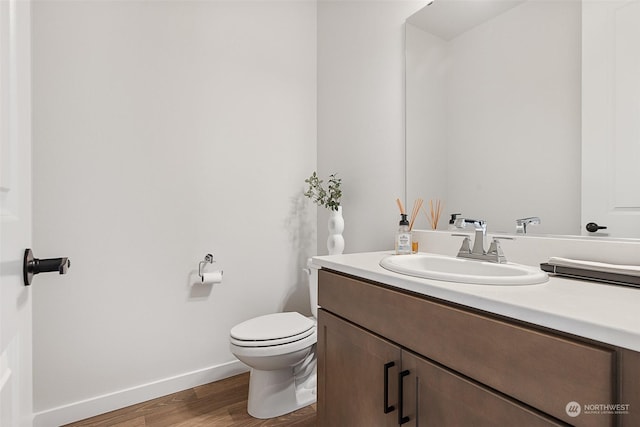 bathroom with hardwood / wood-style floors, vanity, and toilet