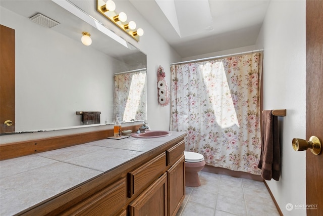 bathroom featuring a skylight, tile flooring, vanity with extensive cabinet space, and toilet