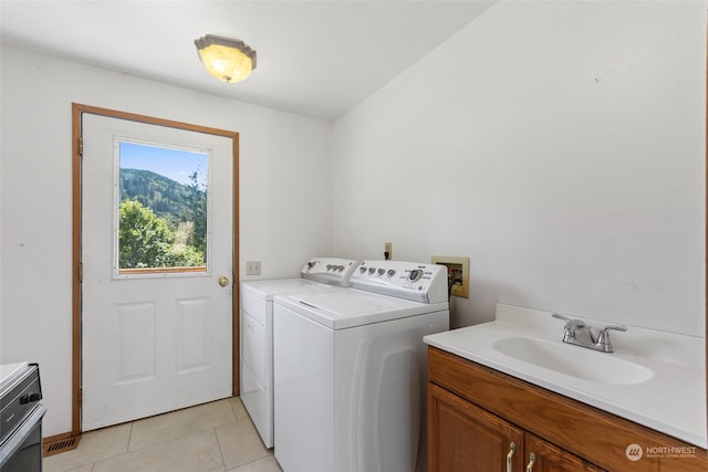 clothes washing area with light tile floors, sink, washing machine and clothes dryer, and hookup for a washing machine