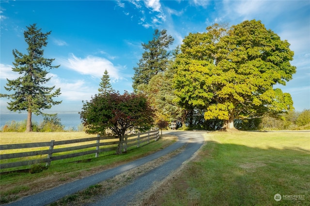 view of property's community with a water view and a lawn