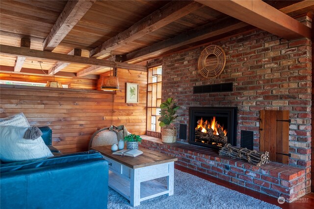 living room with beamed ceiling, wood walls, a brick fireplace, wood ceiling, and carpet floors