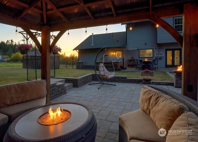 patio terrace at dusk with a gazebo, a fire pit, and a yard