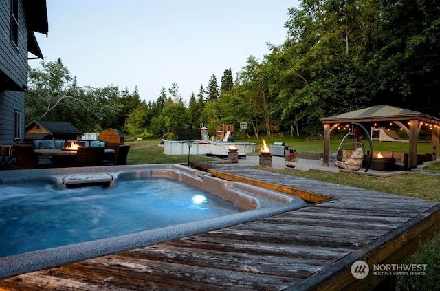 view of swimming pool with a lawn, a gazebo, and a fire pit