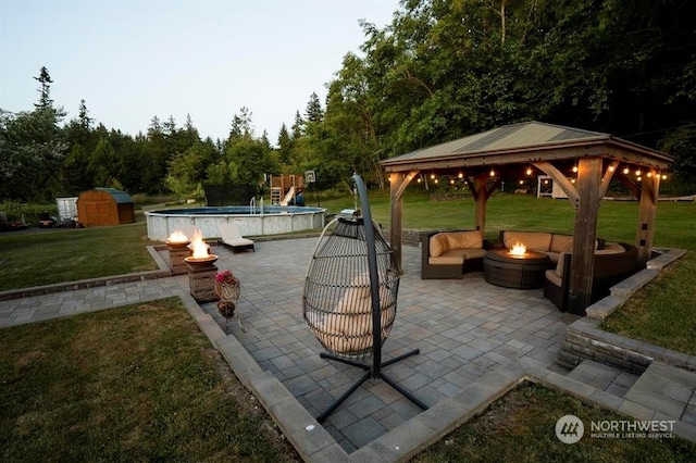 view of patio featuring a gazebo, an outdoor living space with a fire pit, and a shed