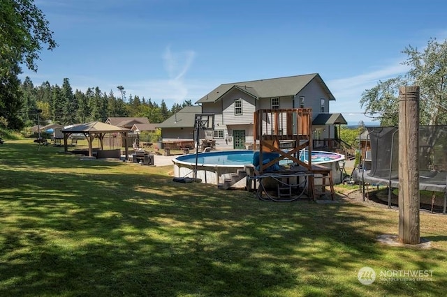 view of swimming pool with a yard, a gazebo, a deck, and a trampoline