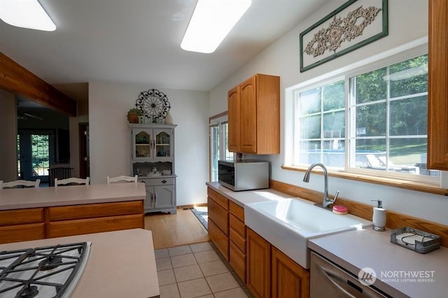 kitchen featuring a healthy amount of sunlight, stainless steel gas stovetop, light tile floors, and sink