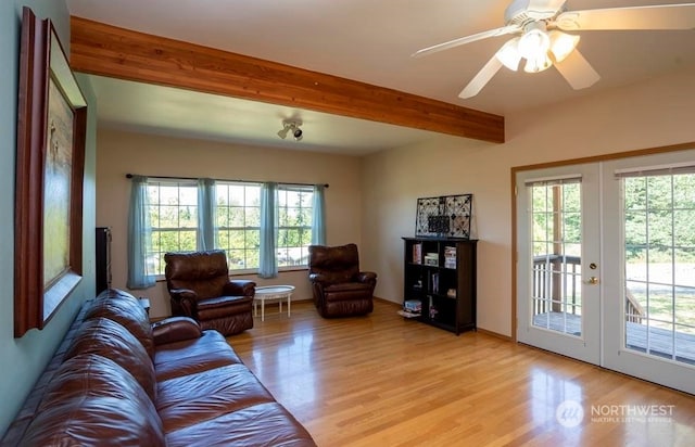 living room featuring a wealth of natural light, ceiling fan, light hardwood / wood-style flooring, and beamed ceiling