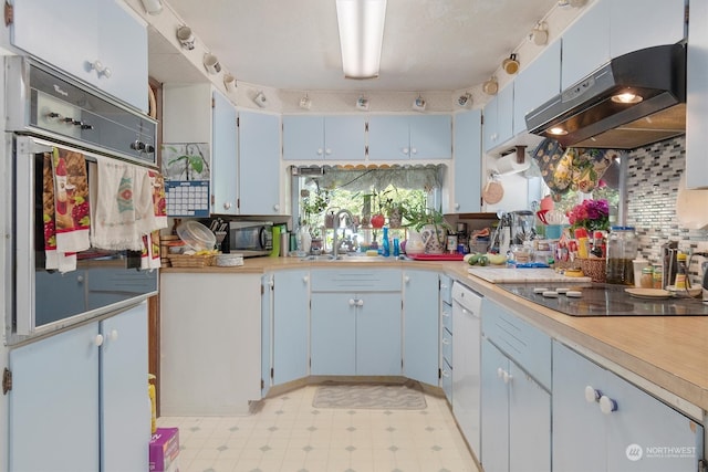 kitchen featuring backsplash, blue cabinets, wall chimney exhaust hood, and sink