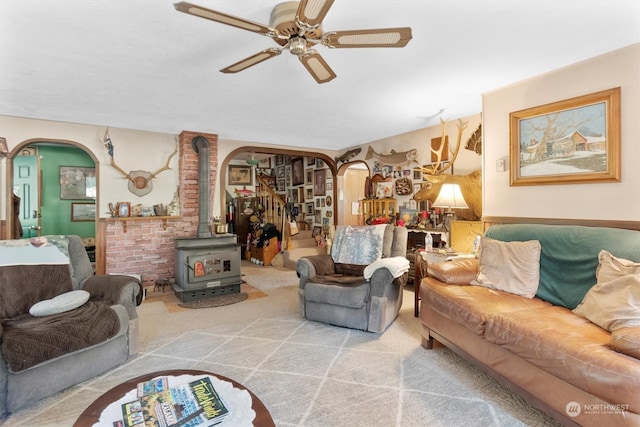 carpeted living room featuring brick wall, ceiling fan, and a wood stove