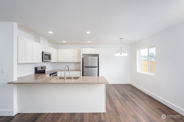 kitchen featuring kitchen peninsula, white cabinets, stainless steel appliances, dark wood-type flooring, and an inviting chandelier