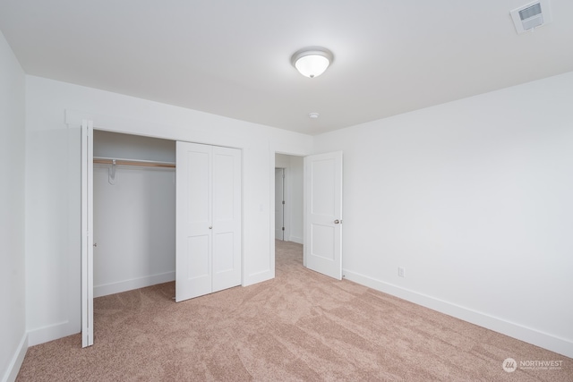 unfurnished bedroom with light colored carpet and a closet