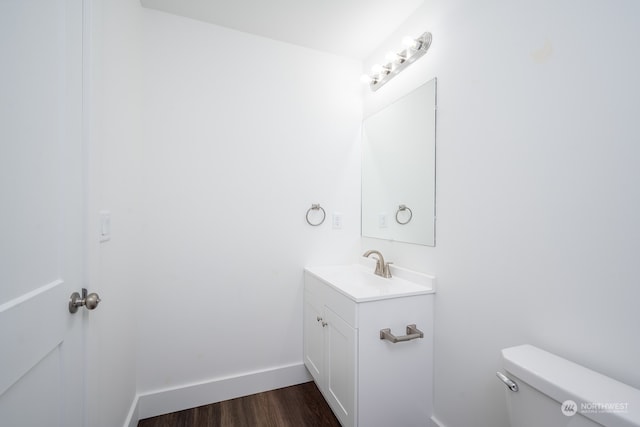 bathroom with toilet, hardwood / wood-style flooring, and vanity with extensive cabinet space