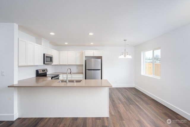 kitchen with dark wood-type flooring, white cabinetry, stainless steel appliances, kitchen peninsula, and a notable chandelier