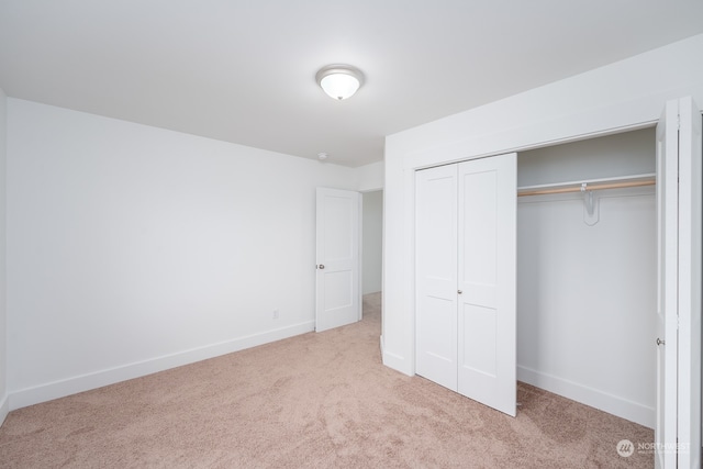 unfurnished bedroom featuring a closet and light colored carpet