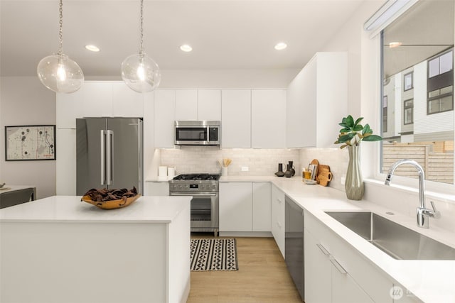 8326C SB-3 13th Ave NW, Seattle, WA 98117 - kitchen featuring high quality appliances, a sink, white cabinetry, tasteful backsplash, and hanging light fixtures