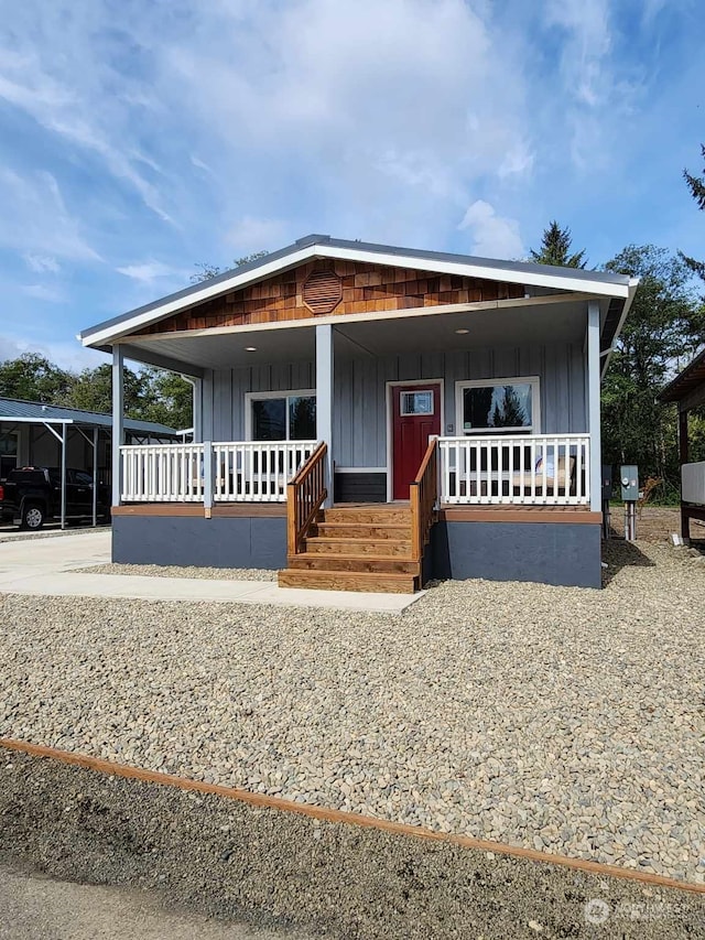 manufactured / mobile home featuring a carport, covered porch, and board and batten siding