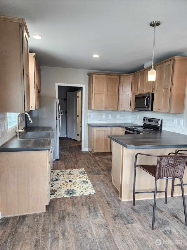 kitchen featuring appliances with stainless steel finishes, dark countertops, dark wood-type flooring, and backsplash