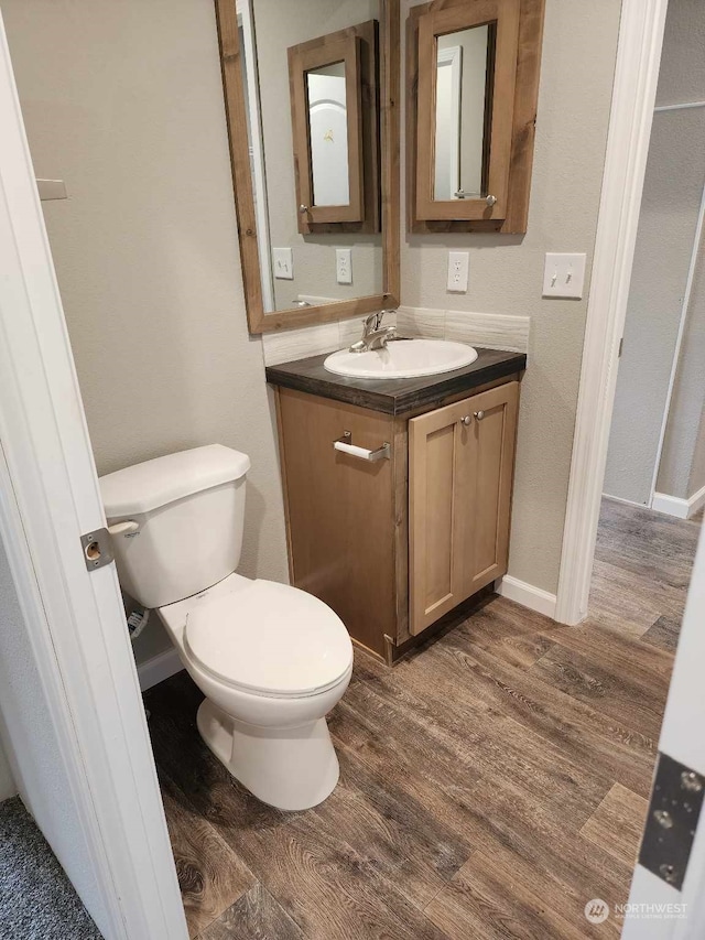 bathroom featuring toilet, wood finished floors, vanity, and baseboards