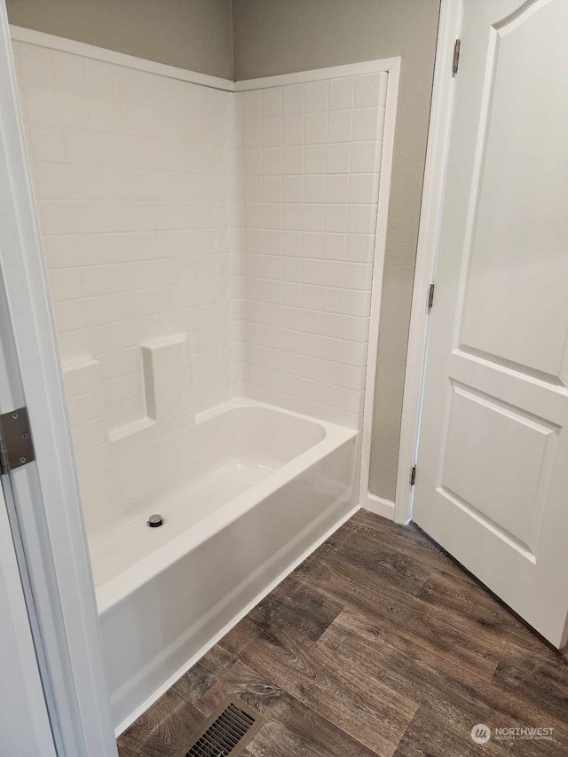 full bath with wood finished floors and washtub / shower combination