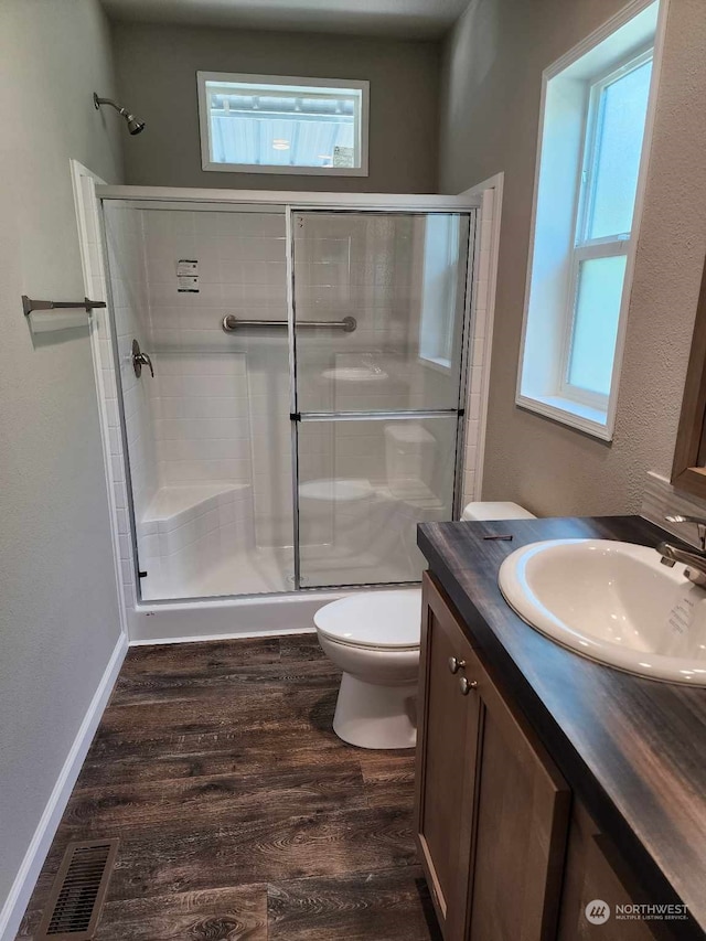 bathroom with a healthy amount of sunlight, visible vents, a shower stall, and wood finished floors