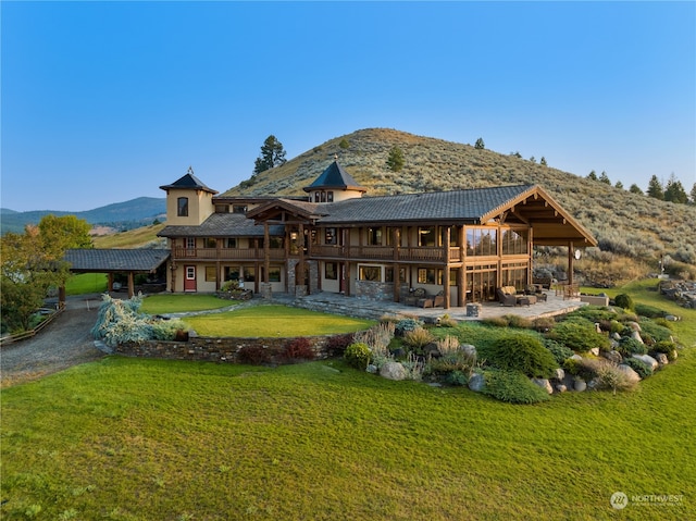 rear view of house featuring a lawn, a patio, and a mountain view