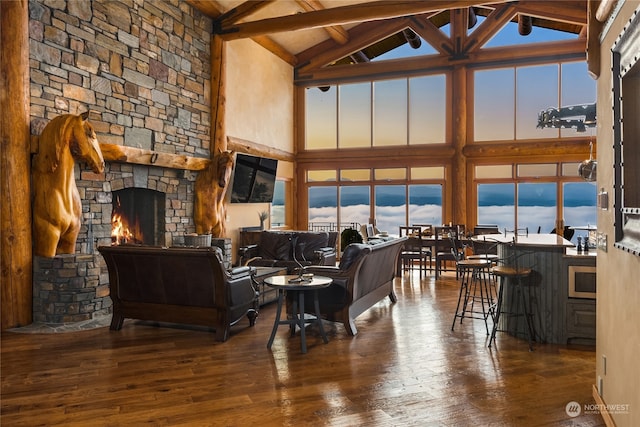 living room featuring a stone fireplace, high vaulted ceiling, dark hardwood / wood-style floors, and beamed ceiling