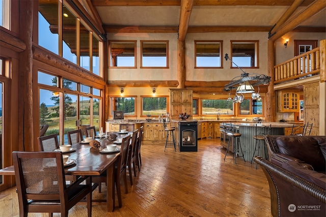 dining space with a high ceiling, beam ceiling, sink, and hardwood / wood-style flooring