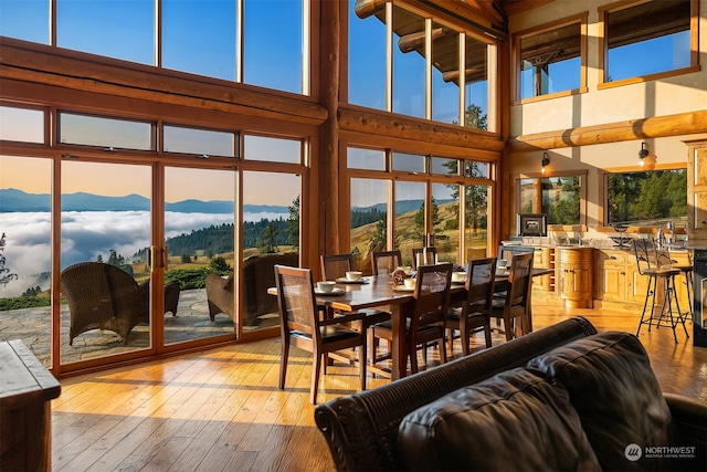 dining space with a towering ceiling, light wood-type flooring, and a mountain view