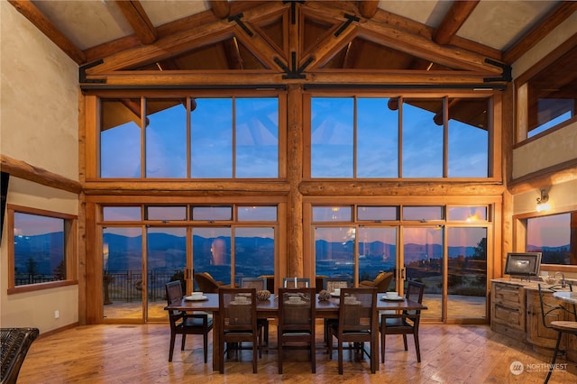 dining room featuring wood-type flooring, beamed ceiling, high vaulted ceiling, and a mountain view