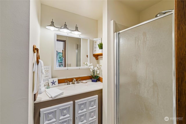 bathroom featuring a shower with shower door and vanity