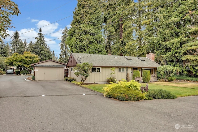 single story home featuring a front lawn, an outdoor structure, and a garage