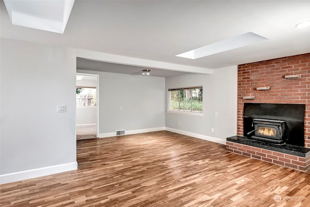 unfurnished living room with a skylight, a wealth of natural light, and wood-type flooring