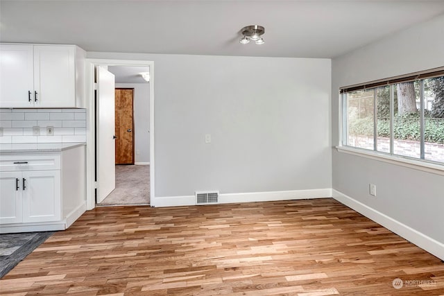 interior space with white cabinetry, tasteful backsplash, and light wood-type flooring