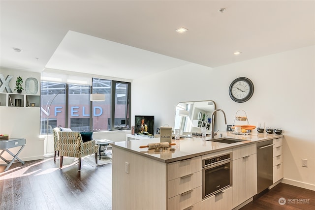 kitchen with dark hardwood / wood-style flooring, sink, appliances with stainless steel finishes, and kitchen peninsula