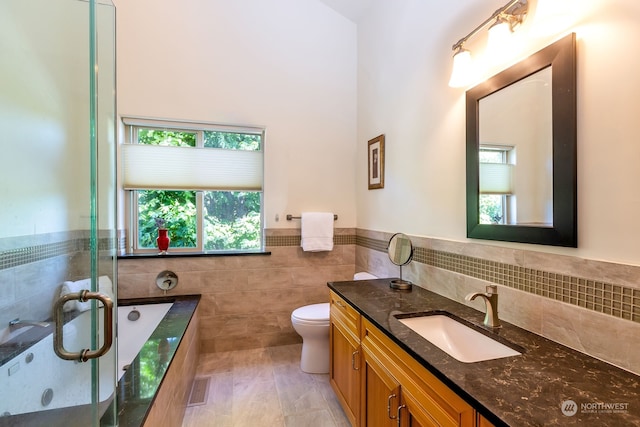 bathroom with vanity, toilet, a bath to relax in, and a wealth of natural light