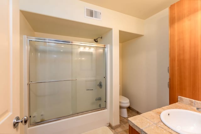 full bathroom featuring bath / shower combo with glass door, vanity, toilet, and tile floors