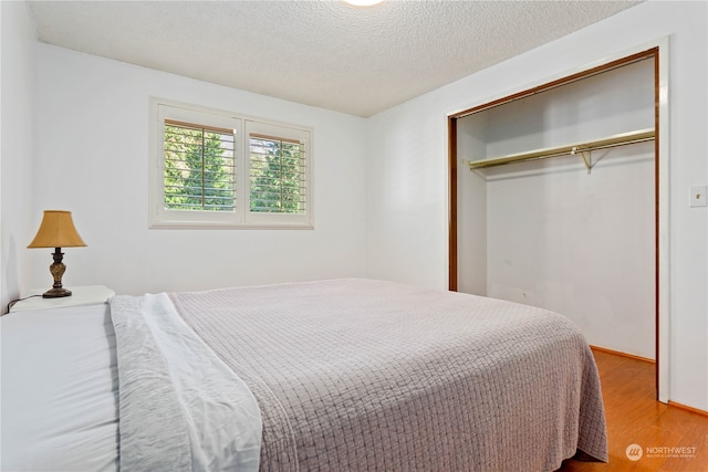 bedroom with a textured ceiling, a closet, and light hardwood / wood-style flooring