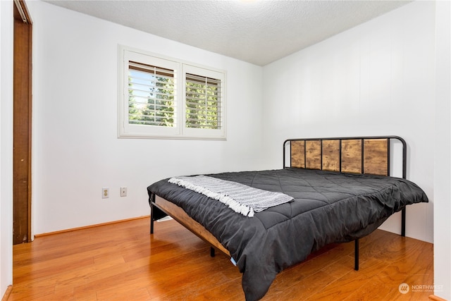 bedroom featuring light hardwood / wood-style flooring and a textured ceiling