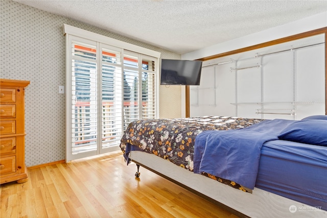 bedroom with a textured ceiling and light hardwood / wood-style floors